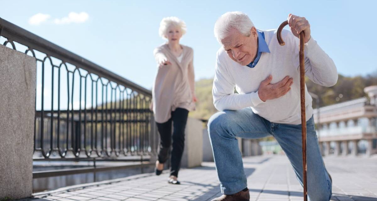 Tips for Handling Health Emergencies in Public 1 An elderly man with a cane crouches down outside while clutching his chest. An elderly woman is behind him.
