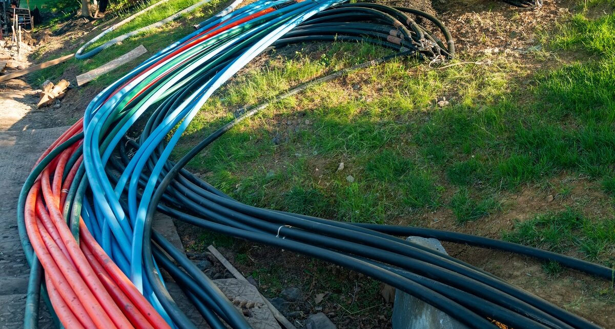 How Traffic Plays a Role in Fiber Network Upkeep 1 A collection of fiber network lines laying on the ground outside. The lines are red, blue, and black.